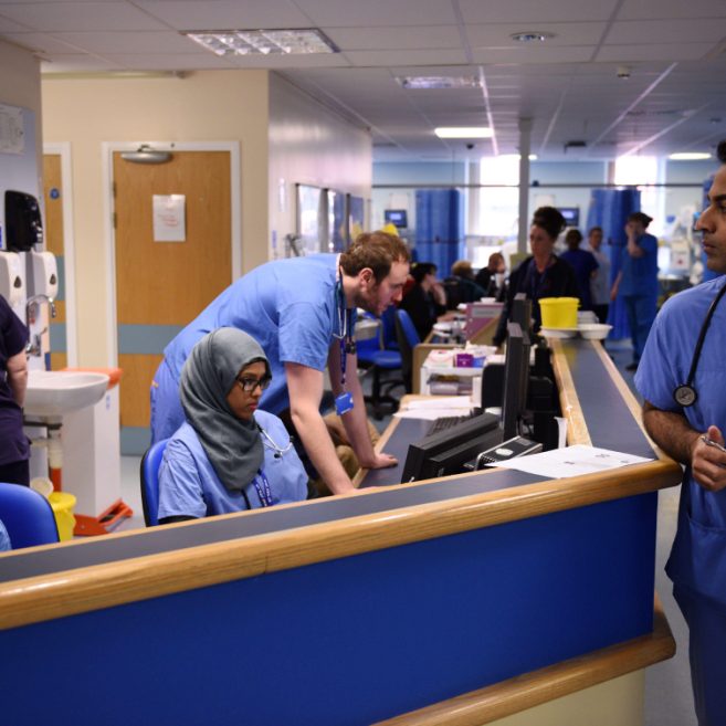 healthcare professionals in blue scrubs working at desks and assisting patients