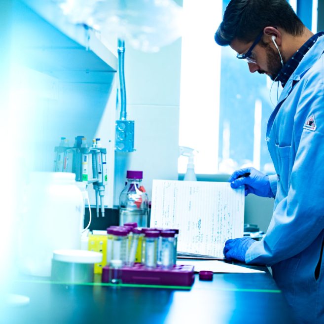 Laboratory professional in a blue lab coat analyzing data and documents
